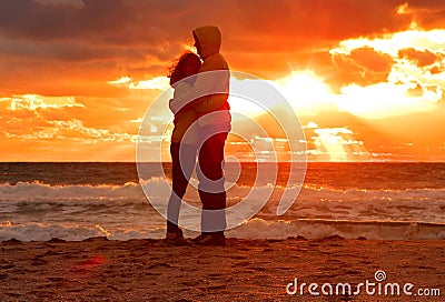 Couple Man and Woman Hugging in Love staying on Beach seaside with Sunset scenery Stock Photo