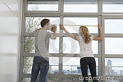 Couple Measuring Apartment Window Stock Photo