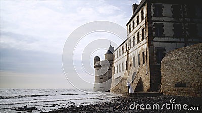 Couple of medieval coastal fortress. Action. Beautiful newlyweds stand at medieval stone fortress built on coast Stock Photo