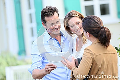 Couple meeting real-estate agent in front of their new home Stock Photo