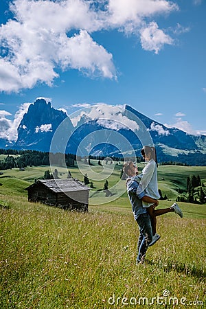 Couple men and woman on vacation in the Dolomites Italy,Alpe di Siusi - Seiser Alm with Sassolungo - Langkofel mountain Stock Photo