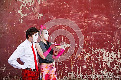 Couple mimes looking aside on the background of a red wall. Stock Photo