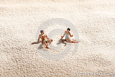 Couple of miniature people relaxing on a beach Stock Photo