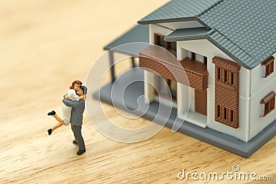 Couple Miniature 2 people standing model with house model make family Feel happy.as background real estate and family concept with Stock Photo