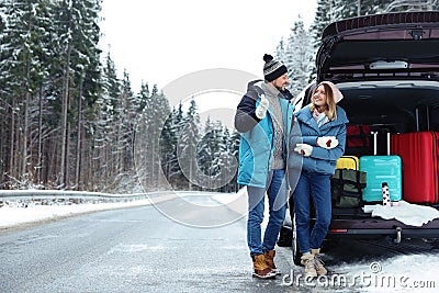 Couple near open car trunk full of luggage on road, space for text Stock Photo