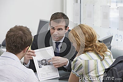 Couple Observing Brochure With Real Estate Agent Stock Photo