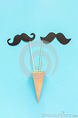 Couple paper mustache props on stick in ice cream waffle cone on blue background. Concept Homosexuality gay love. International Stock Photo
