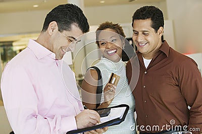 Couple Paying Through Credit Card In Furniture Store Stock Photo