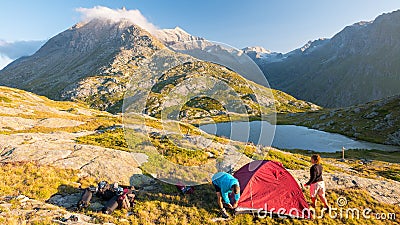 Couple of people setting up a camping tent on the mountains, time lapse. Summer adventures on the Alps, idyllic lake and summit. Stock Photo