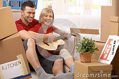 Couple playing guitar together in new house Stock Photo