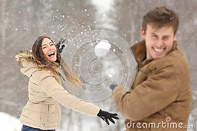 Couple playing with snow and girlfriend throwing a ball Stock Photo