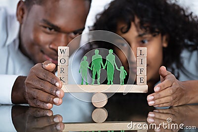 Couple Protecting Work And Life Balance On Seesaw Stock Photo