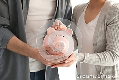 Couple putting coin into piggy bank, closeup. Money savings concept Stock Photo