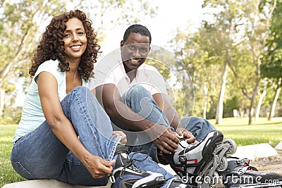 Couple Putting On In Line Skates In Park Stock Photo