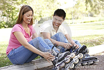 Couple Putting On In Line Skates In Park Stock Photo