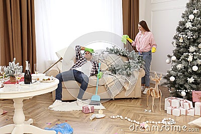 Couple quarrelling in messy room while cleaning after New Year party Stock Photo