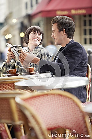 Couple Reading Guidebook At Outdoor Cafe Stock Photo