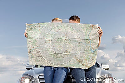 Couple reading map while leaning on car hood during road trip Stock Photo