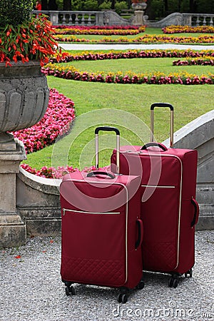 Couple of red suitcases in front of ornamental flowerbeds. Mirabell palace gardens. Park in Salzburg town in Austria Stock Photo