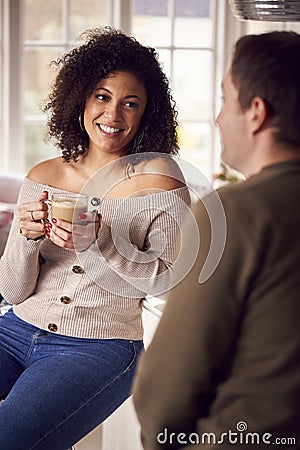Couple Relaxing At Home Sitting At Kitchen Counter With Coffee Stock Photo