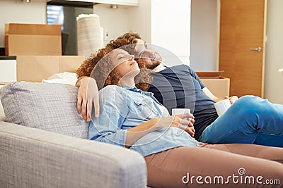 Couple Relaxing On Sofa With Hot Drink In New Home Stock Photo