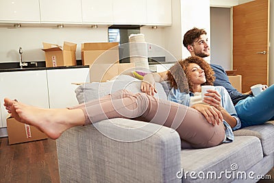 Couple Relaxing On Sofa With Hot Drink In New Home Stock Photo