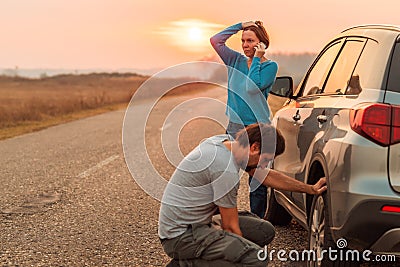 Couple repairing car flat tire on the road Stock Photo