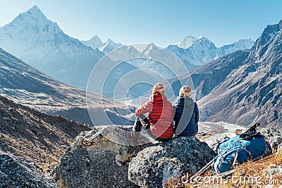 Couple resting on the Everest Base Camp trekking route near Dughla 4620m. Backpackers left Backpacks and trekking poles and Stock Photo