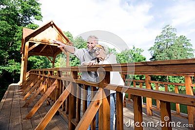 Couple of retired man and woman having rest standing on big wooden bridge Stock Photo
