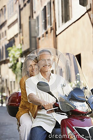 Couple Riding Scooter On Street Stock Photo