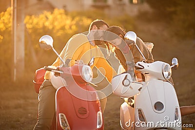 Couple on romantic road trip on scooter at sunset on vacation Stock Photo