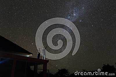 Couple on rooftop watching mliky way and catching stars in the night sky on Bali island Stock Photo