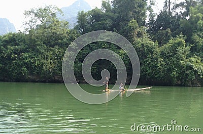 Couple rowing cross green clear river by bamboo simple boat Editorial Stock Photo