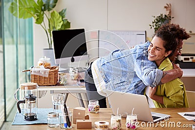 Couple Running Online Business Making Boutique Candles At Home Celebrating With Hug Stock Photo