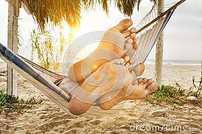 Couple`s Feet on Edge of Hammock on Beach Stock Photo