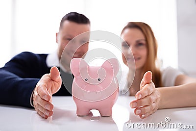 Couple`s Hand Protecting Piggybank Stock Photo