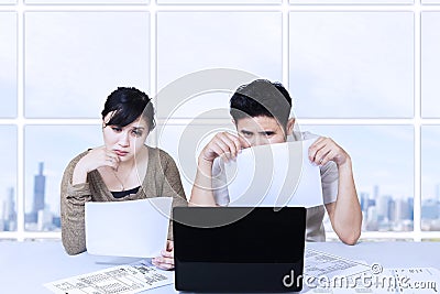 Couple sad looking at laptop in office Stock Photo