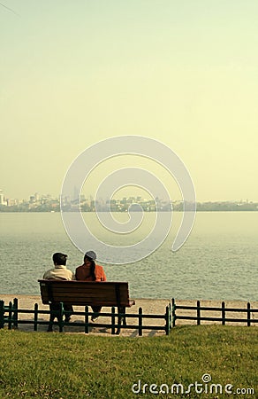 Couple sat on bench by lake Stock Photo