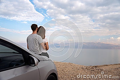 Couple seated on the engine hood of a rented car on a road trip in israel Stock Photo