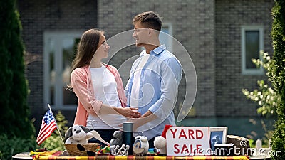 Couple selling second hand things on yard sale and looking at each other, fun Stock Photo