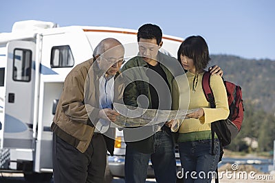 Couple and senior father reading map outside RV Stock Photo