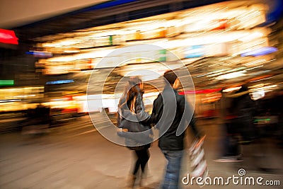 Couple with shopping bags walking past at dusk Editorial Stock Photo