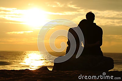 Couple silhouette watching sunset on the beach Stock Photo