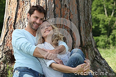 Couple sitting against a tree Stock Photo