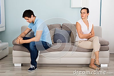 Couple Sitting Back To Back On Sofa Stock Photo