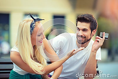 Couple sitting on the bench, the girl wants to take a credit card Stock Photo