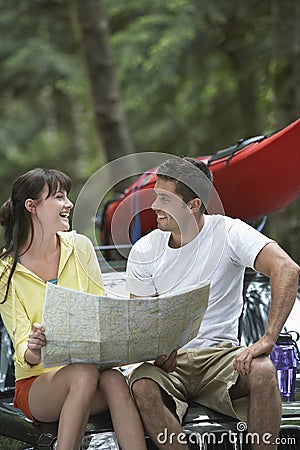 Couple Sitting On Car With Map Stock Photo