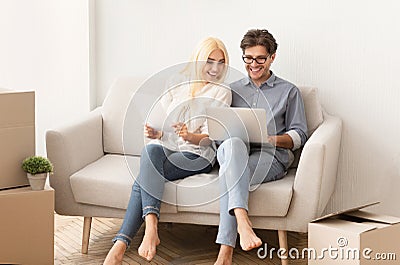 Couple sitting on couch reading design project documents on laptop Stock Photo