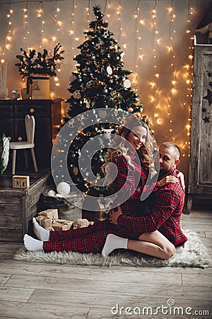 Couple sitting embraced at Christmas tree. Stock Photo