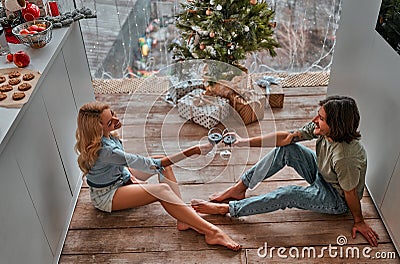 Couple sitting on the kitchen floor in their new home, making a toast with glasses of wine, celebrating New year. Top view Stock Photo